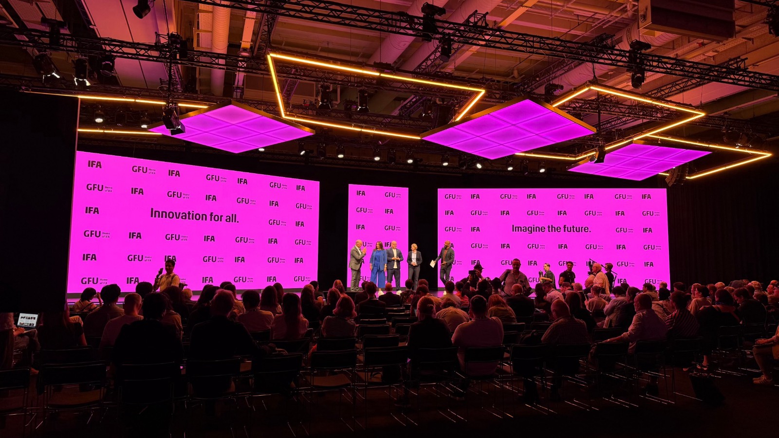 Keynote stage with three LED walls and illuminated LED ceiling panels in front of a full audience