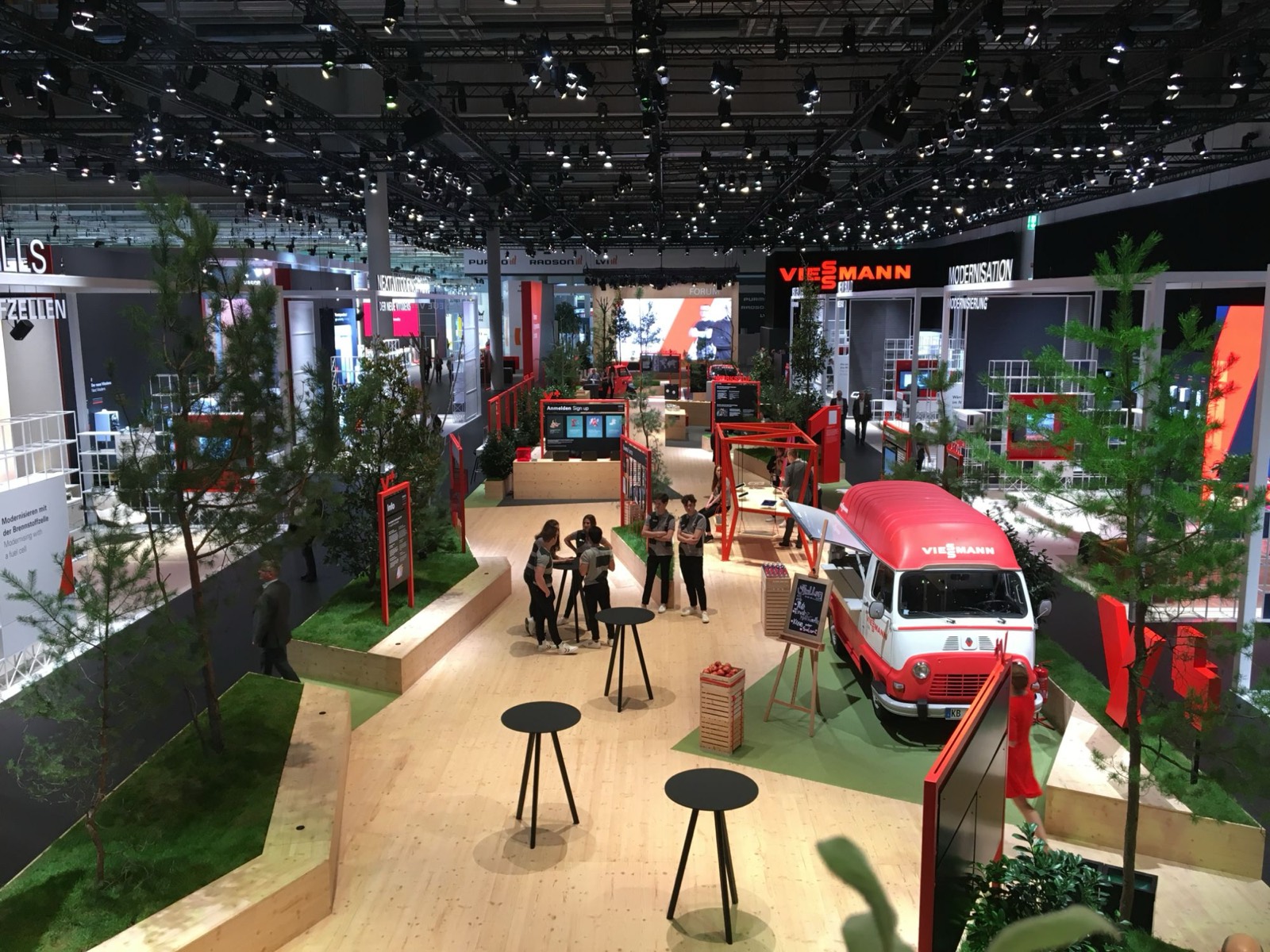Large trade show stand with wooden flooring, trees and LED surfaces